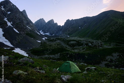 Camping tent of green color near the Chaukhi mountain range in Georgia at sunset. photo