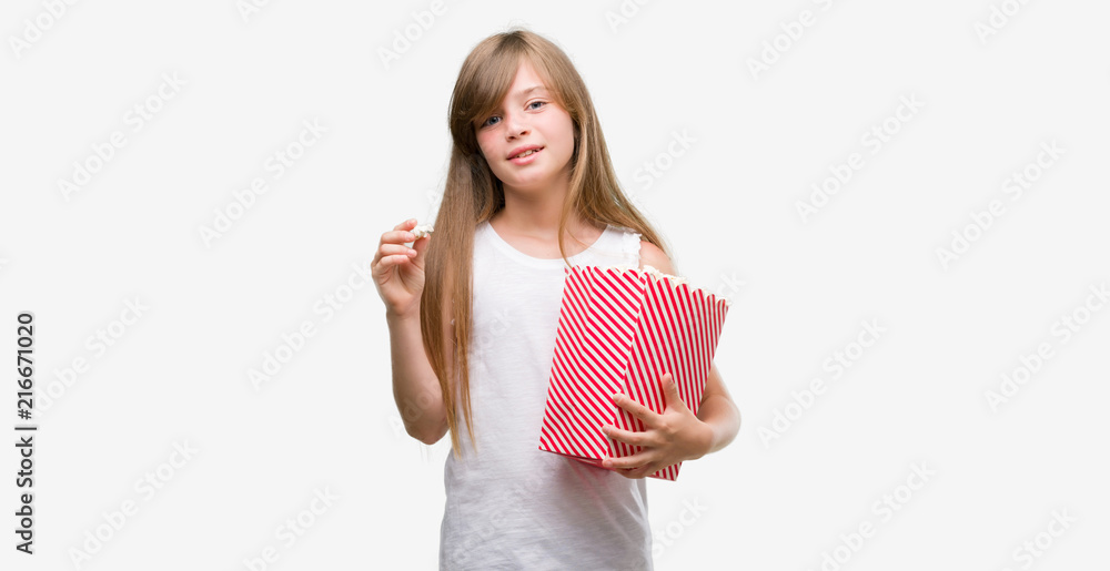 Young blonde toddler holding popcorn pack with a happy face standing and smiling with a confident smile showing teeth Young blonde toddler holding popcorn pack with a happy face standing and smiling with a confident smile showing teeth