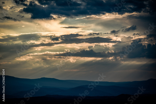 Beautiful clouds with sun penetrating them during sunset. © Kozioł Kamila