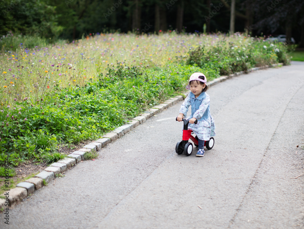 baby girl play bike in Summer forest park baby girl play bike in Summer forest park