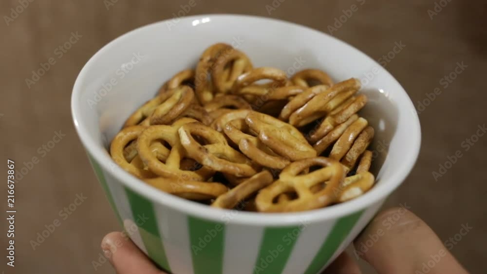 cookies in the shape of small pretzels is in the plate. Male and female white-skinned hands take one liver from the plate. Close-up, indoors, real time cookies in the shape of small pretzels is in the plate. Male and female white-skinned hands take one liver from the plate. Close-up, indoors, real time