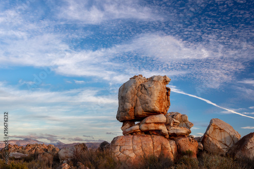 A dramatic rock formation etched against a blue sky with fluffy white clouds in the Kagga Kamma Nature Reserve in South Africa