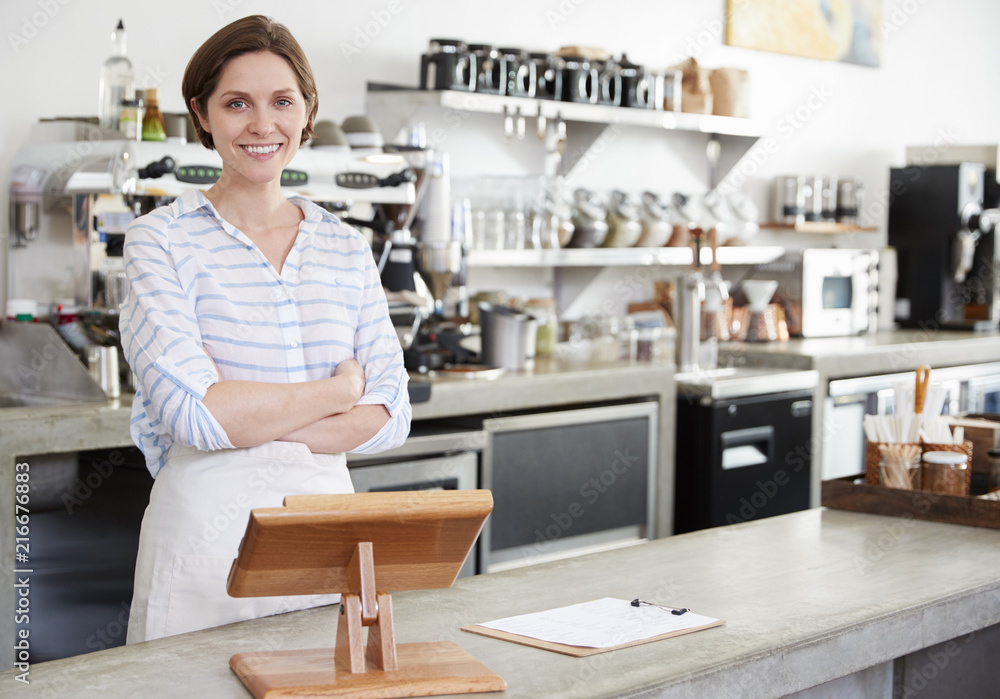 Smiling woman behind counter at a coffee shop, arms crossed Smiling woman behind counter at a coffee shop, arms crossed