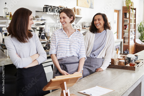 Three female cafe owners looking at each other in cafe