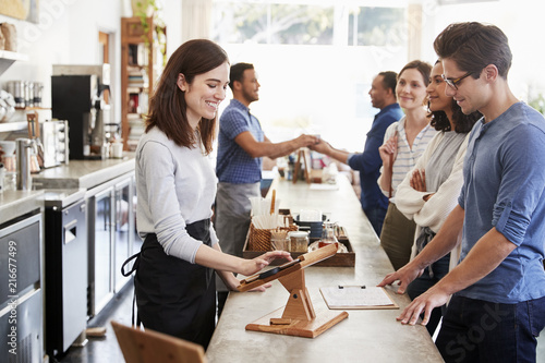 Obraz na plátne Customers queuing to order and pay at a coffee shop counter