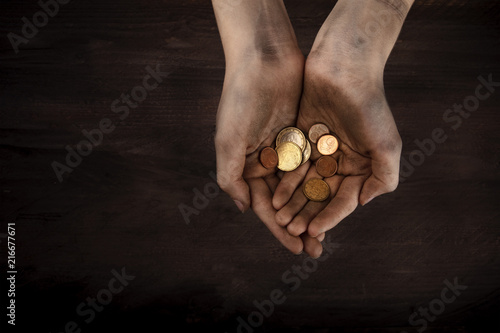 Dirty child's hands with a handful of small coins, poverty symbol, with copy space