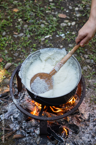 Cook gomi (mamaliga porridge) - popular dish from Samegrelo region made of white coarse cornmeal, butter and salt in big kettle on open fire. Georgian traditional food. photo