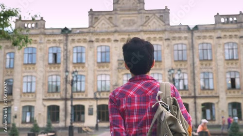 Back view of young female student with short black hair walking to university, woman going to college daytime