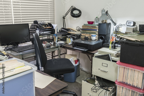 Messy business office desk with boxes of files and disorganized clutter. photo