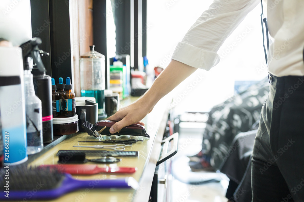 Hair Expert Keeping Trimmer On Counter In Salon Hair Expert Keeping Trimmer On Counter In Salon