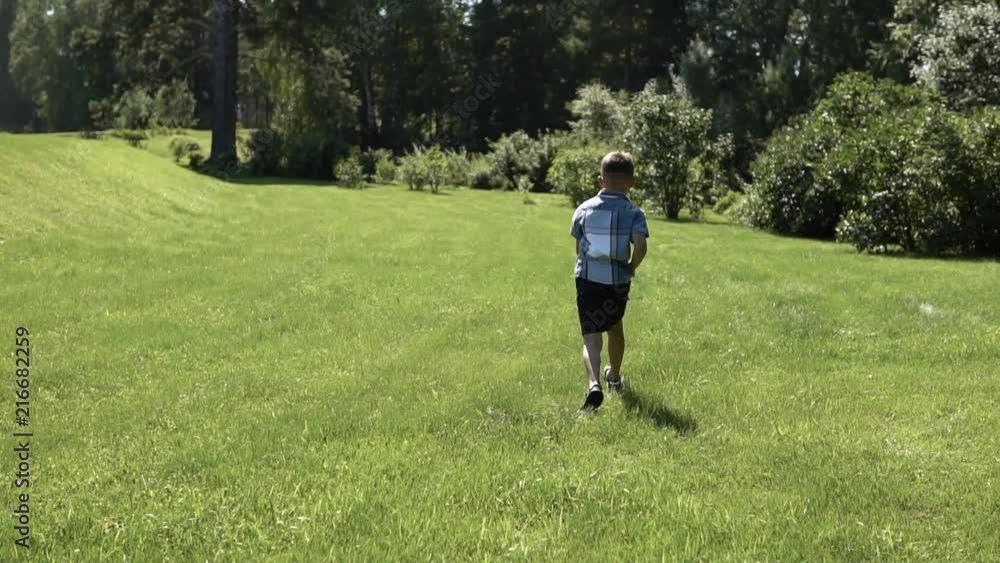attractive boy runs along the grass in the park having a good mood. slow motion attractive boy runs along the grass in the park having a good mood. slow motion