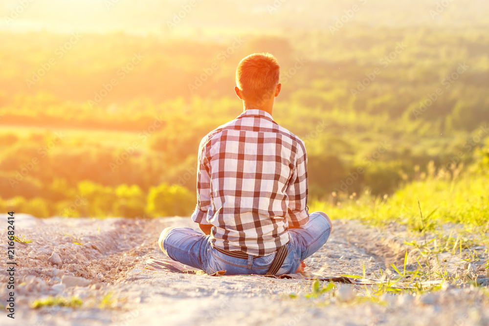 young man sitting in Lotus position with beautiful view at sunset