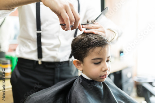 Boy Having Haircut With Comb And Scissors At Barber Shop
