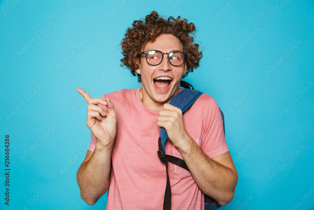 Photo of hipster geek man with curly hair wearing glasses and backpack  smiling and gesturing aside, isolated over blue background foto de Stock |  Adobe Stock