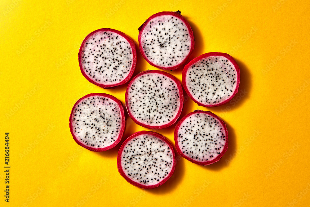 Flat lay view of background from round slices of Dragon fruit or Pitaya on a yellow background. Flat lay view of background from round slices of Dragon fruit or Pitaya on a yellow background.