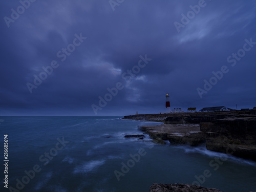 Summer sunrise with stormy clouds and slow shutter speed at Portland Bill Light, Dorset, UK