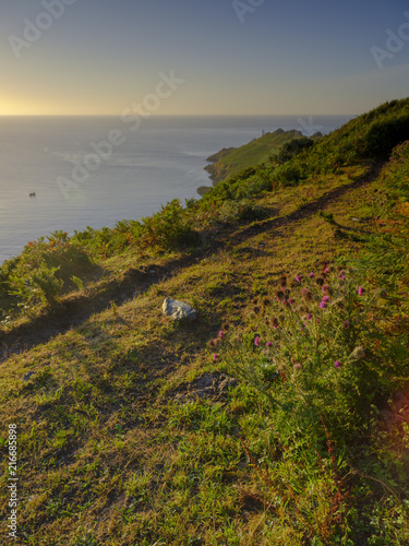 Summer sunrise on a clear day on the Start Point peninsula and light house on the south Devon coast, UK photo