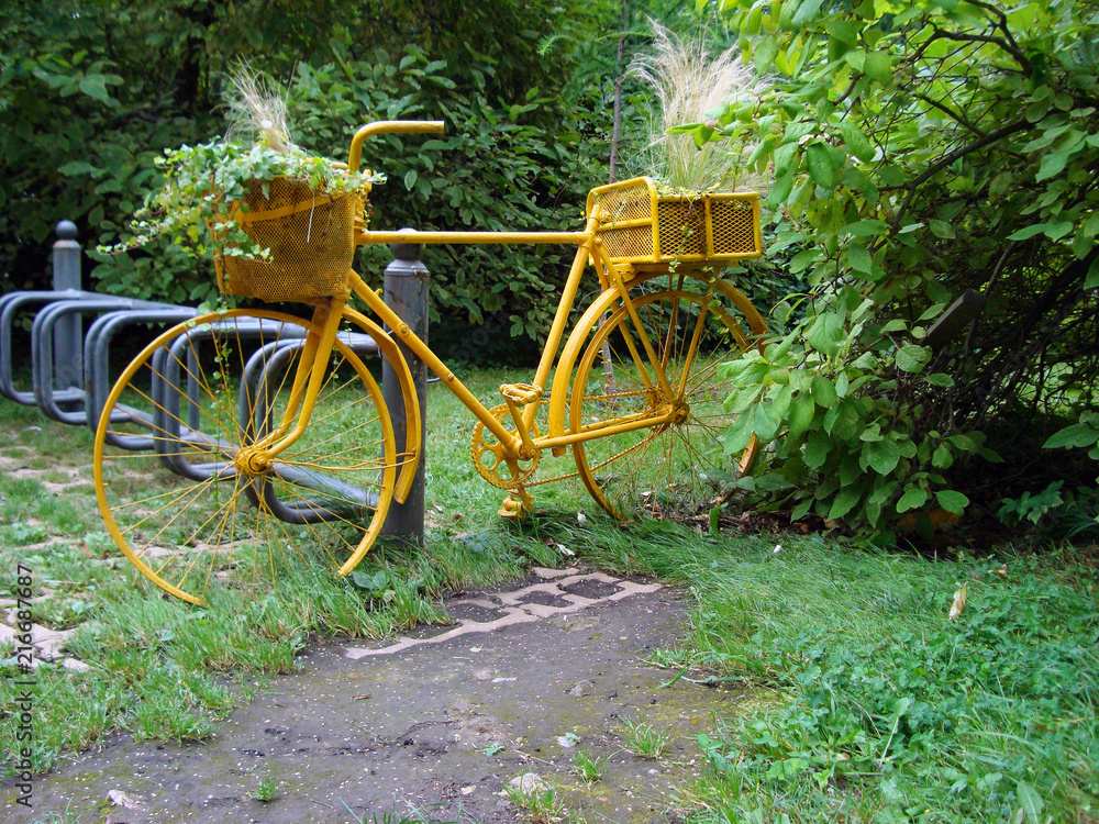 Yellow old bike in the Park with flower pots.