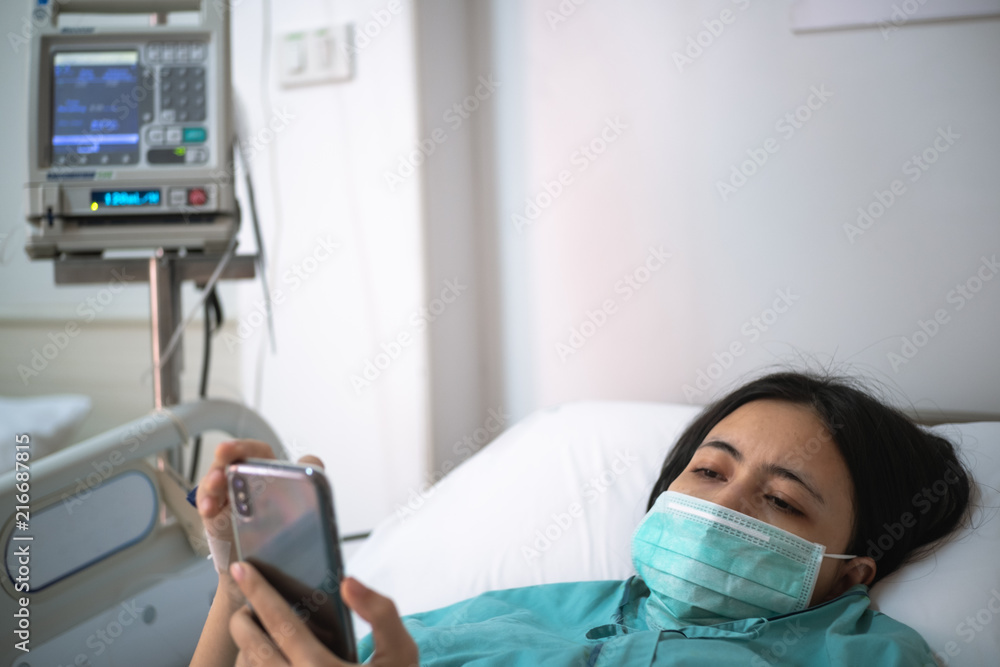 young woman patient lay on bed in hospital and use smartphone young woman patient lay on bed in hospital and use smartphone