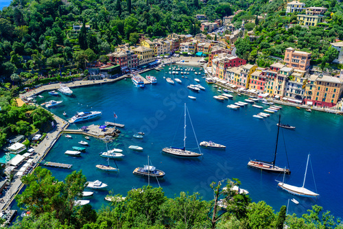 Portofino, Italy - colorful houses and yacht in little bay harbor. Liguria, Genoa province, Italy. Italian fishing village with beautiful sea coast landscape in summer season. © Simon Dannhauer