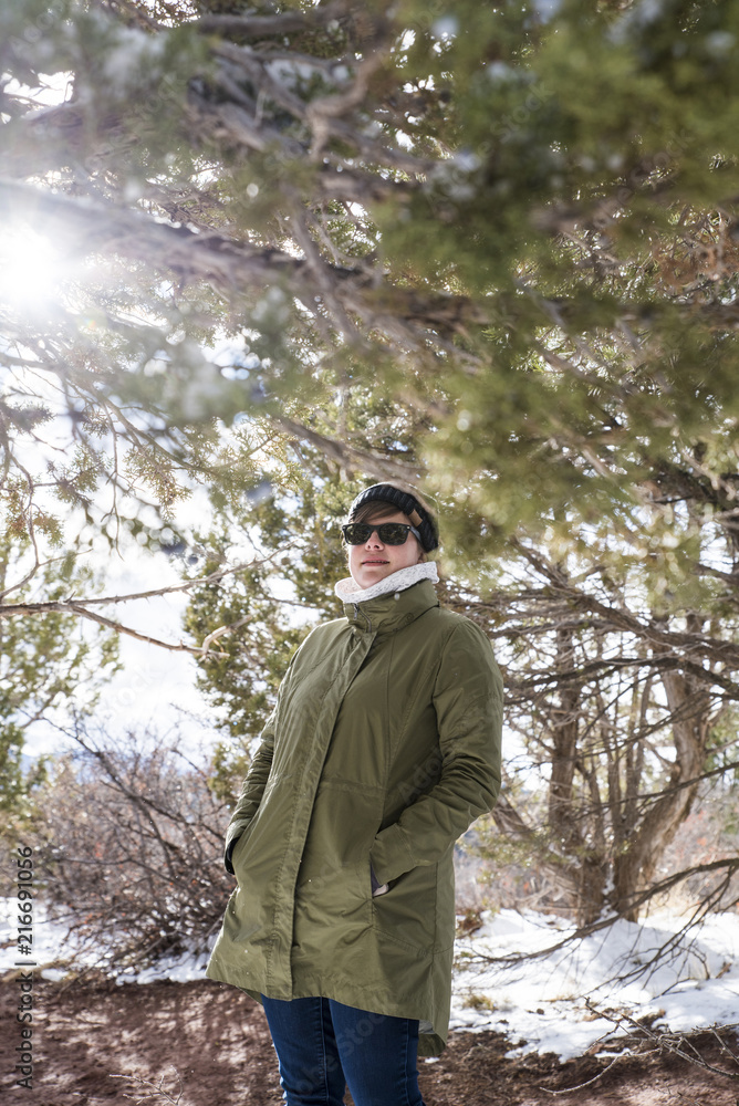 Woman with hands in winter coat's pockets standing by branches at desert during winter