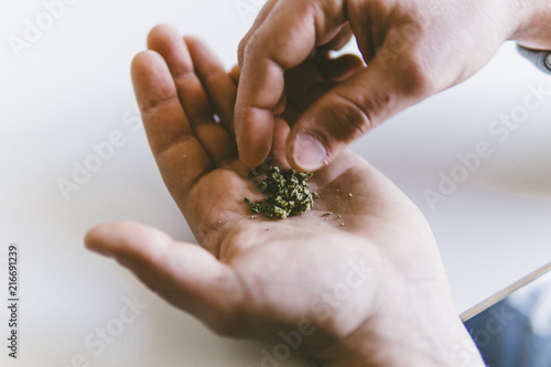 Cropped hands of man making marijuana joints at home photo