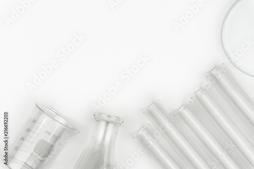 top view of laboratory equipments. A flask, test tubes, watch glass and beaker on the white table