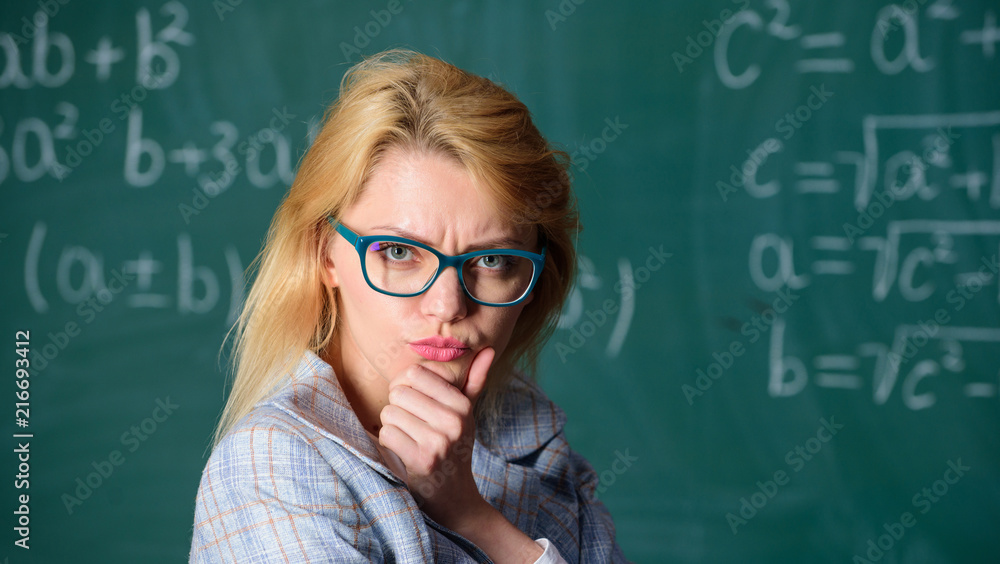 Solve mathematics task. Solve that task. School education basic knowledge. Lady wear eyeglasses smart teacher classroom chalkboard background, close up. Teacher woman think about solving and result Solve mathematics task. Solve that task. School education basic knowledge. Lady wear eyeglasses smart teacher classroom chalkboard background, close up. Teacher woman think about solving and result