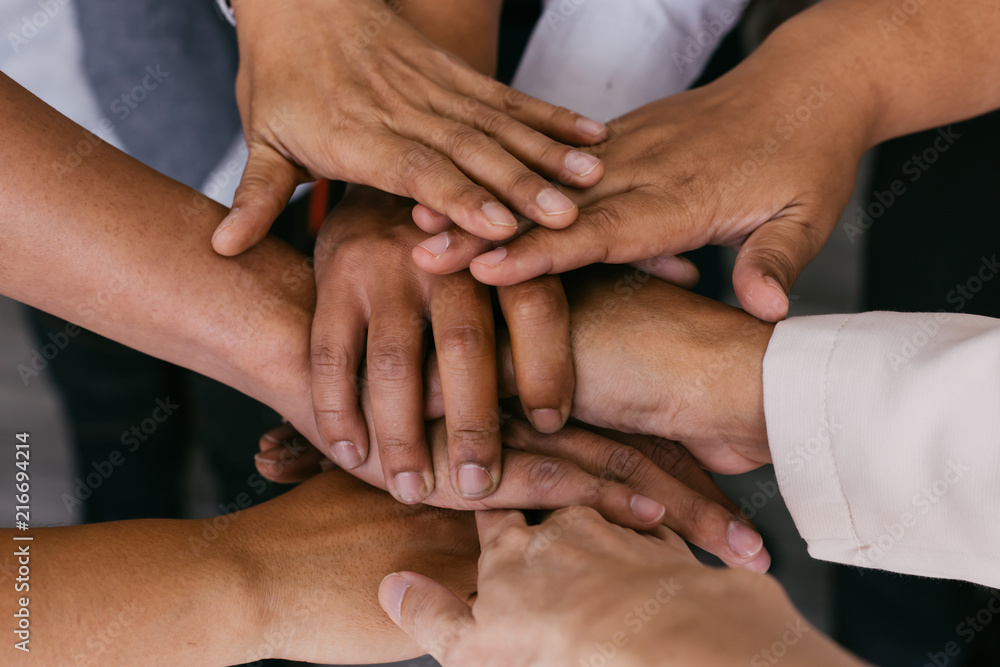 Close up of young business people putting their hands together for unity. Hands stacking over for collaboration and teamwork Close up of young business people putting their hands together for unity. Hands stacking over for collaboration and teamwork