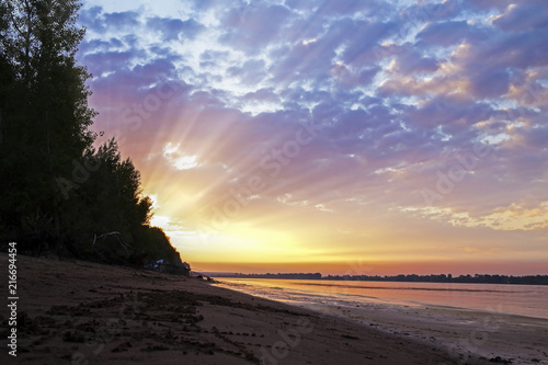 amazing sunset on the background of a river with beautiful clouds in the Golden rays of the sun