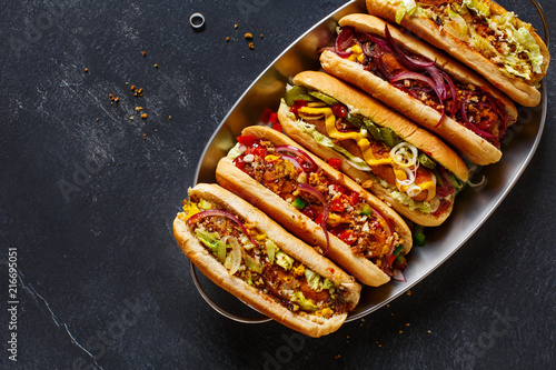 Canvas Print Hot dogs fully loaded with assorted toppings on a tray.