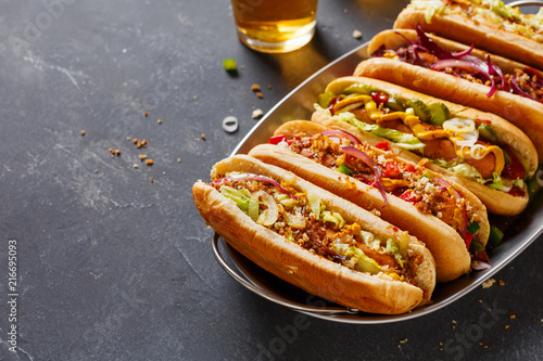 Fotografi Hot dogs fully loaded with assorted toppings on a tray.