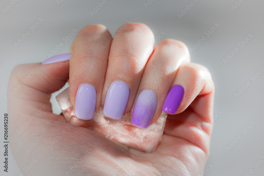 Cooling summer manicure with ice crystal. On the nails of lilac and brightly violet summer shade, the toning of the ambre is sprinkled with glitters, like snow. The effect of cold. Cooling summer manicure with ice crystal. On the nails of lilac and brightly violet summer shade, the toning of the ambre is sprinkled with glitters, like snow. The effect of cold.