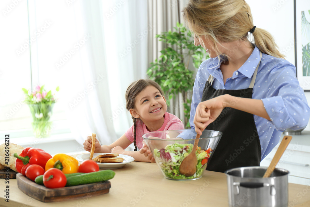 Young nanny with cute little girl cooking together in kitchen Young nanny with cute little girl cooking together in kitchen