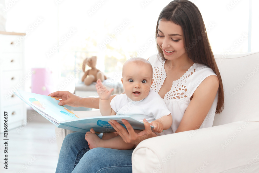 Young mother with her cute baby girl reading book in armchair at home Young mother with her cute baby girl reading book in armchair at home