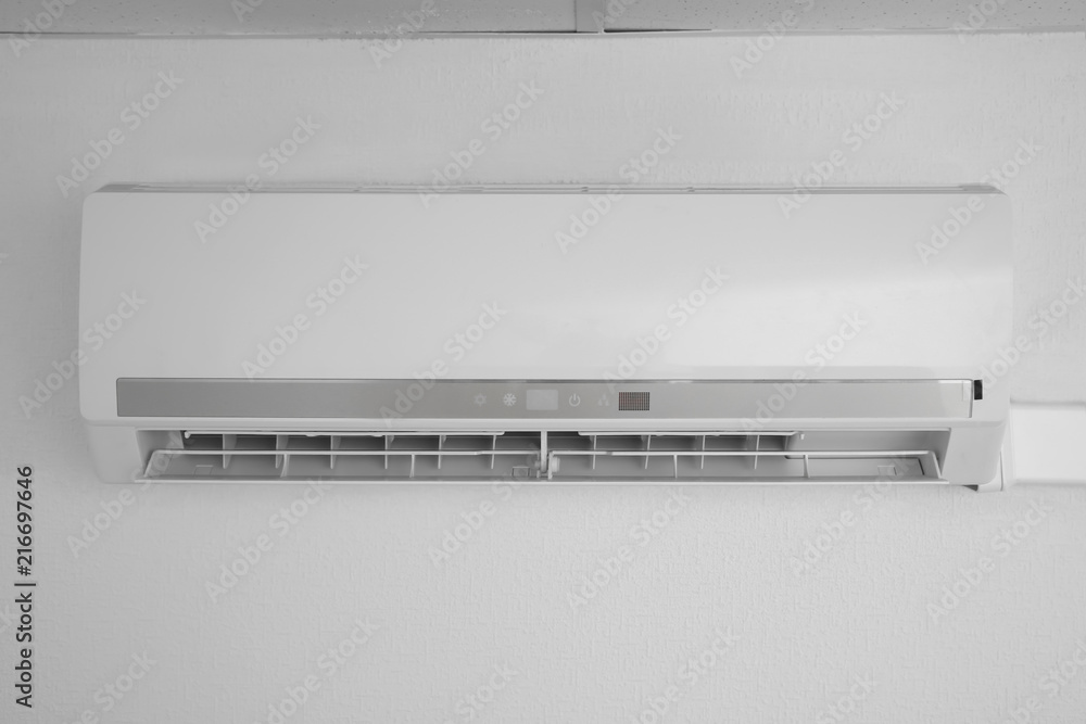 Modern air conditioner on white wall indoors Modern air conditioner on white wall indoors