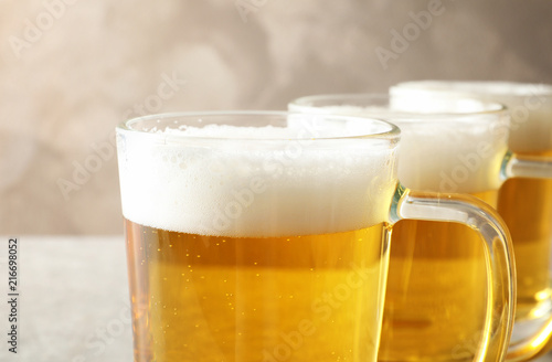 Glass mugs of cold tasty beer on table, closeup