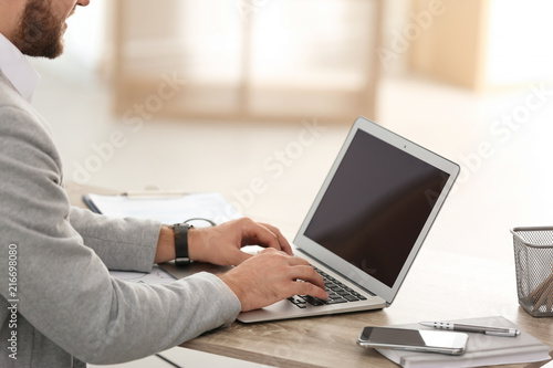 Young businessman using laptop at table in office