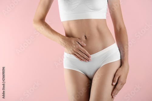 Fototapeta Naklejka Na Ścianę i Meble -  Young woman holding hands near panties on color background. Gynecology concept