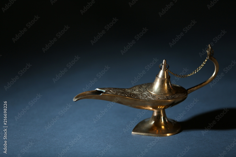 Aladdin lamp of wishes on table against dark background Aladdin lamp of wishes on table against dark background