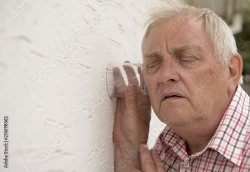 Foto Nosy neighbour holding a glass up to the wall