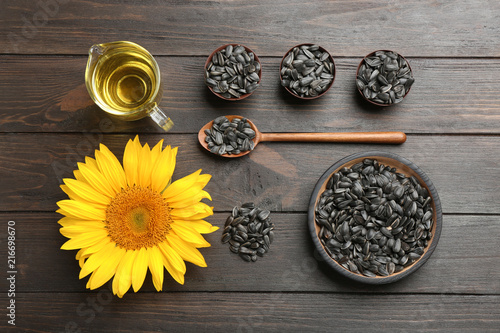 Fototapeta Naklejka Na Ścianę i Meble -  Flat lay composition with sunflower seeds and flower on wooden table