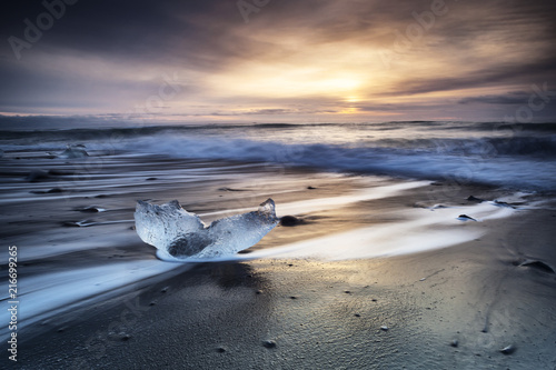 Jokulsarlon beach at sunrise, long exposure photography with waves and pieces of ice on the black sand beach. photo