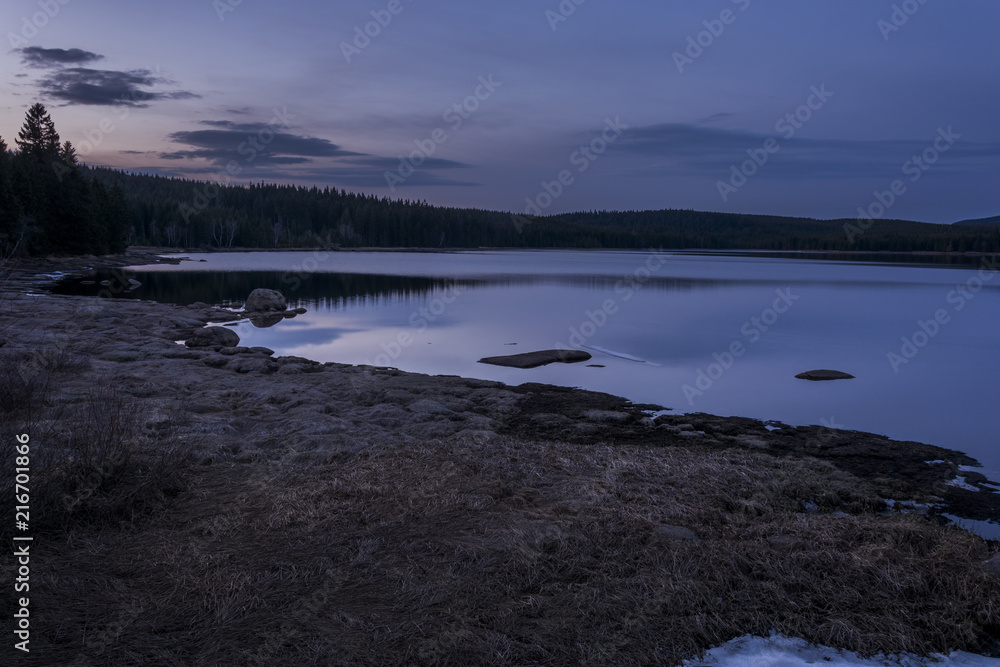 Dark and quiet water surface of the dam in the mountains. Evening nature in spring. Dark and quiet water surface of the dam in the mountains. Evening nature in spring.