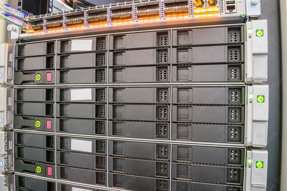 Modern database servers with multiple hard drives work in the server rack. The computing equipment is located in the data center. Cloud farm. Modern database servers with multiple hard drives work in the server rack. The computing equipment is located in the data center. Cloud farm.