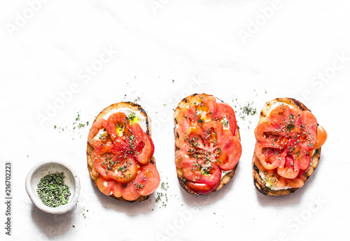 Heirloom tomatoes, feta cheese, oregano bruschetta on a light background, top view. Delicious appetizers, tapas, snack photo