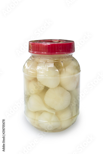 Pickled garlic in transparent plastic bottle packing on a white backdrop.