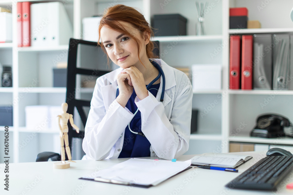A beautiful young girl in a white robe is sitting at a table in the office. A beautiful young girl in a white robe is sitting at a table in the office.