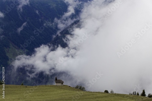 Cloudy alpine landscape with a small chapel