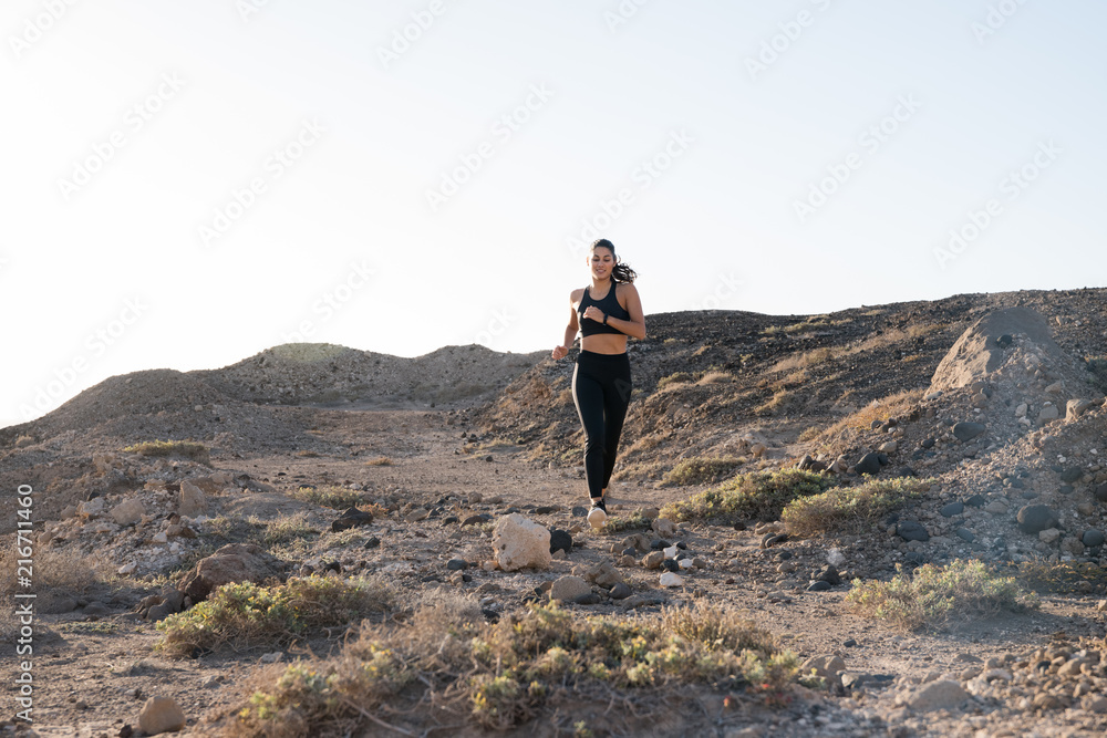 Woman jogging in the desert along a rocky path